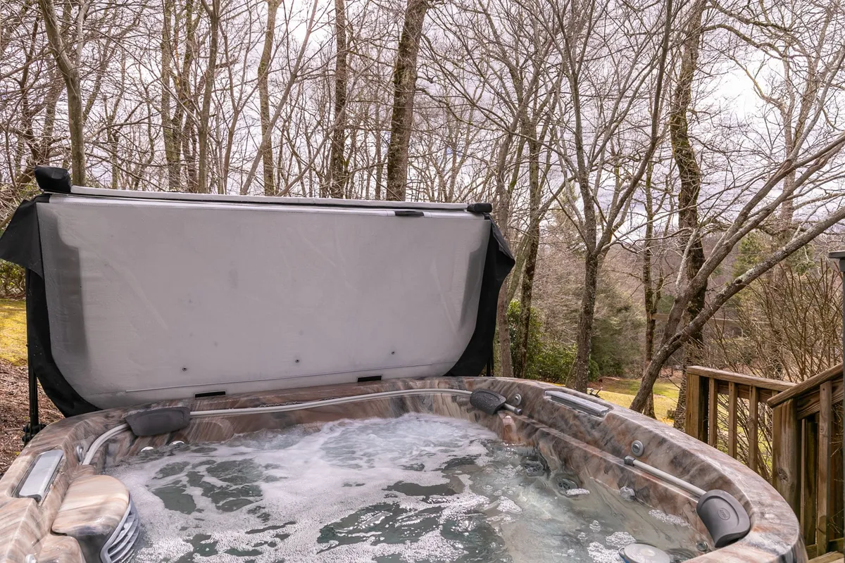 This image showcases a bubbling hot tub on a deck, surrounded by trees and nature. The setting is tranquil, ideal for relaxing or socializing while enjoying the fresh mountain air and scenic views.