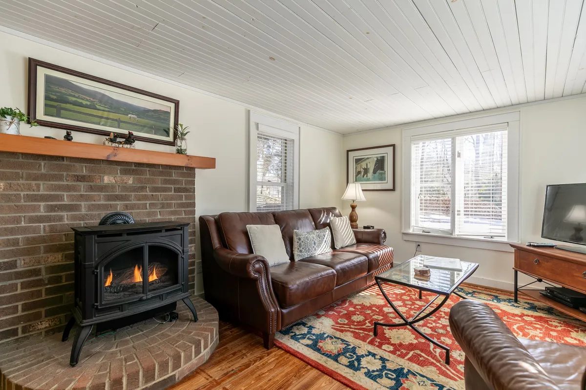 A warm living space featuring a fireplace, leather sofa, coffee table, and wall art. The area feels intimate and inviting, ideal for relaxing with family or friends, enjoying the warmth from the fire, and gathering for conversation or entertainment.